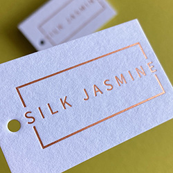 Swing tags hot foil printed with satin copper on white frost colorplan.